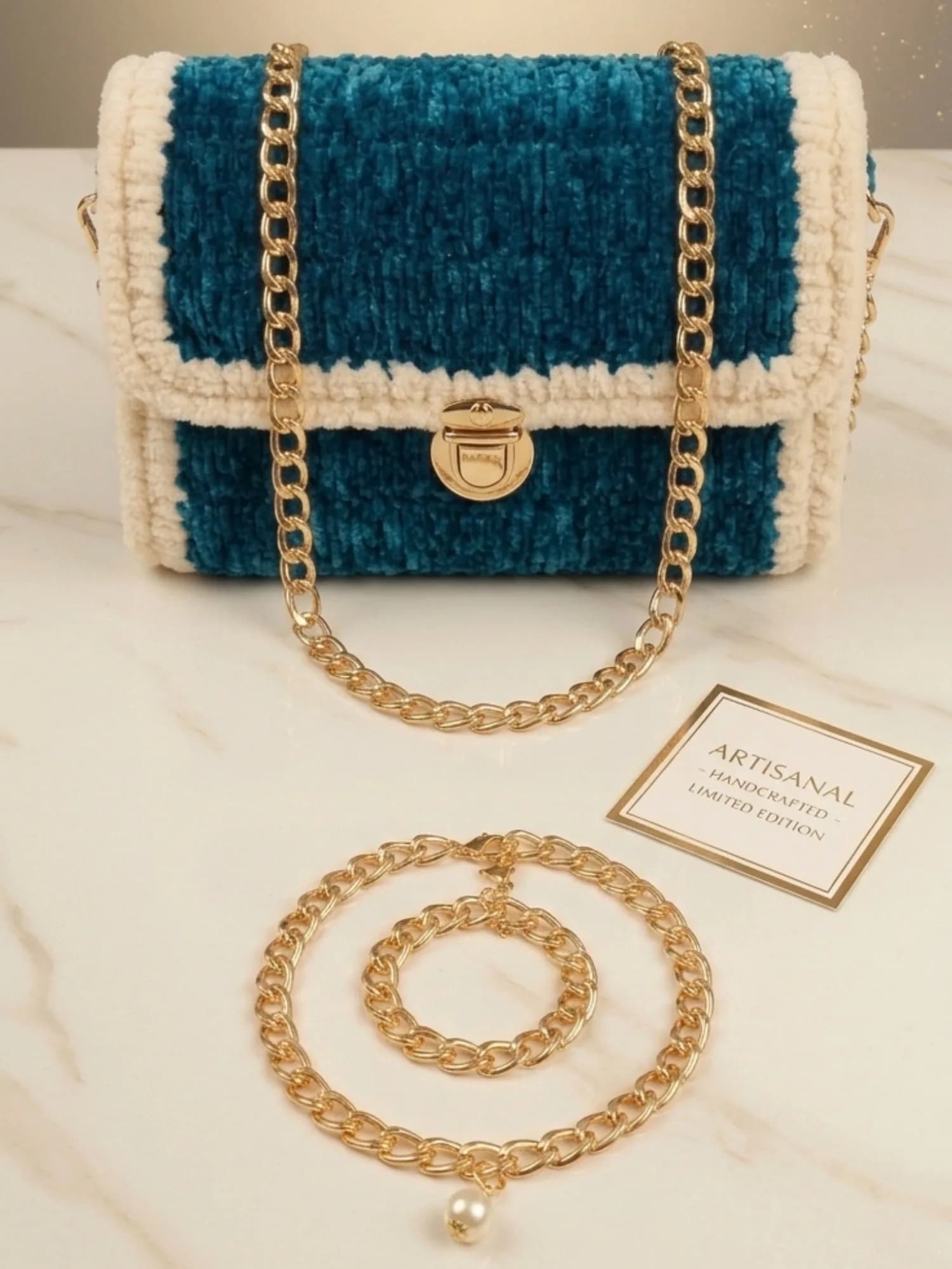 Handmade crochet handbag in teal blue with ivory border carried by its gold chain