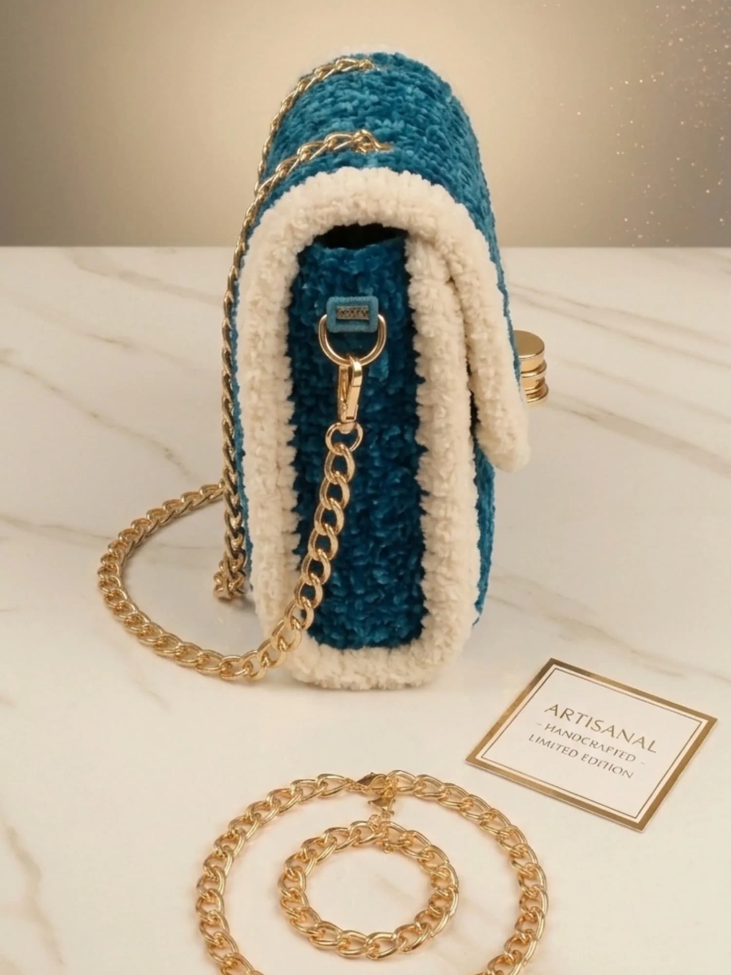Side profile of teal and ivory crochet purse showing gold chain hook and flap
