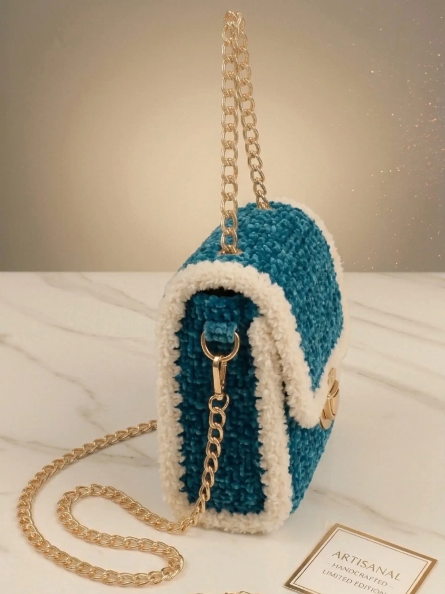 Back of teal crochet bag with ivory edges and gold chain strap